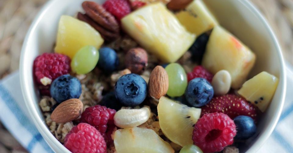 A bowl of muesli topped with fresh berries, pineapple and nuts